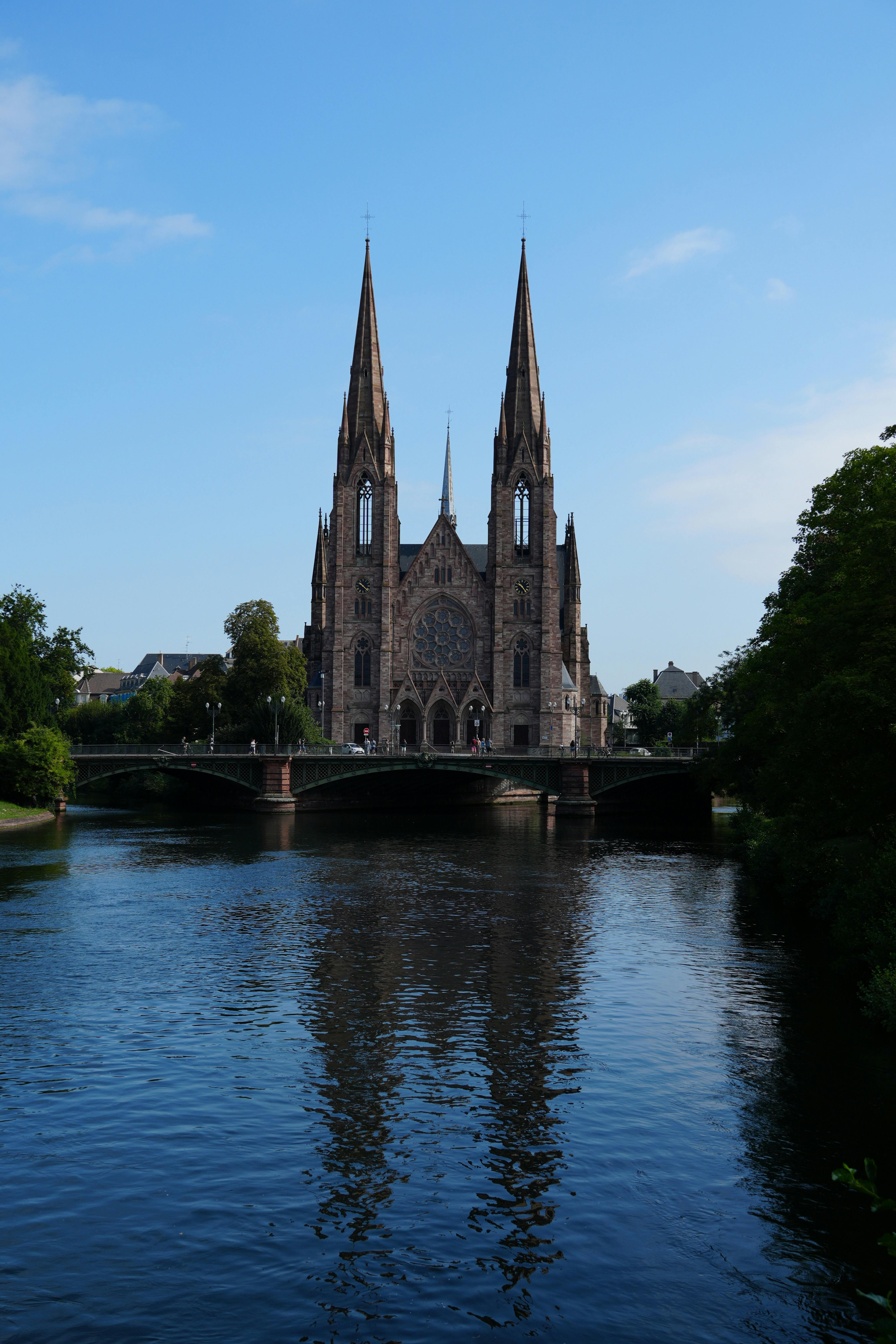 Stunning view of a Gothic cathedral with river reflection on a sunny day.