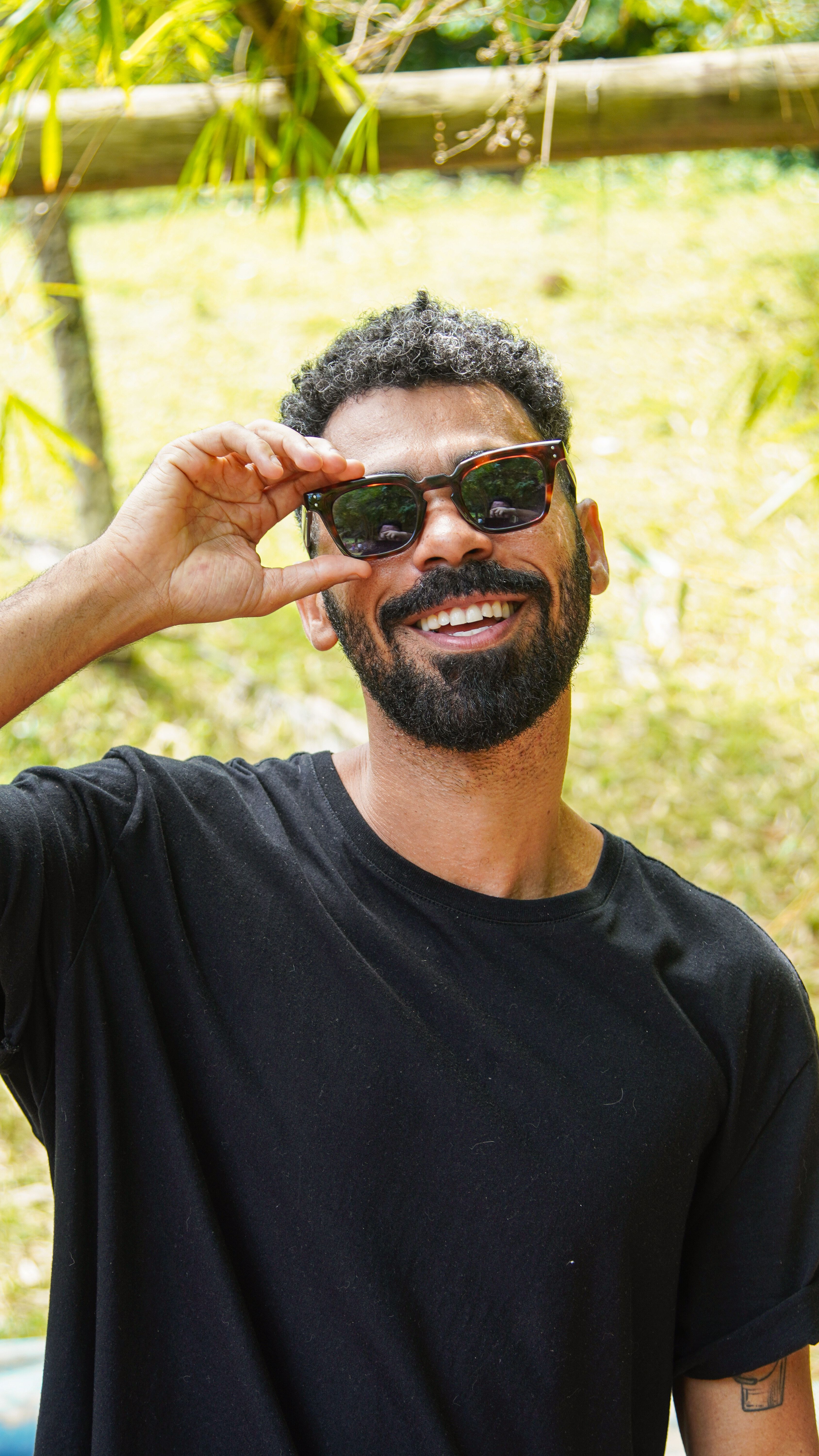 Cheerful man wearing sunglasses enjoys a sunny day outdoors in Bahia, Brazil.