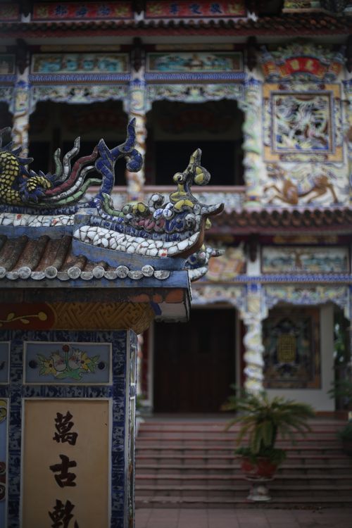 Free Close-up of a temple's ceramic dragon detail with colorful facade backdrop. Stock Photo