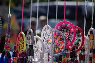 Vibrant handmade dreamcatchers with beads hanging at an outdoor market.