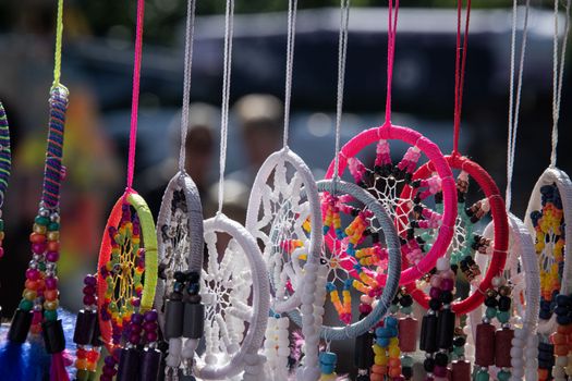 Vibrant handmade dreamcatchers with beads hanging at an outdoor market.