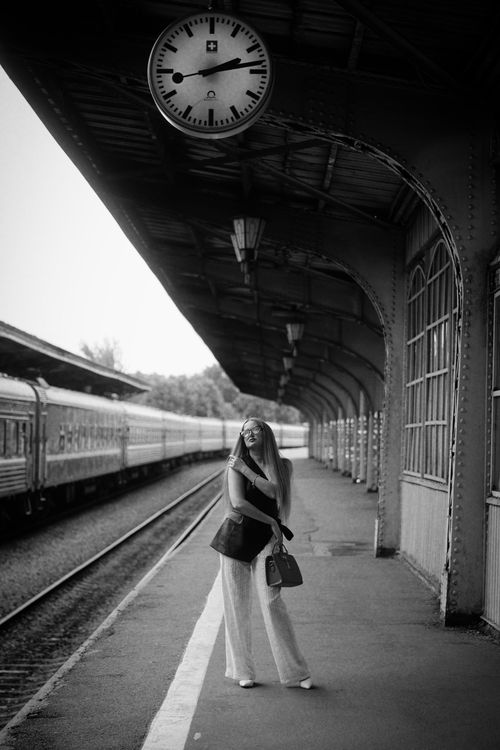 Free Black and white photo of a woman on a vintage train platform, evoking nostalgia. Stock Photo