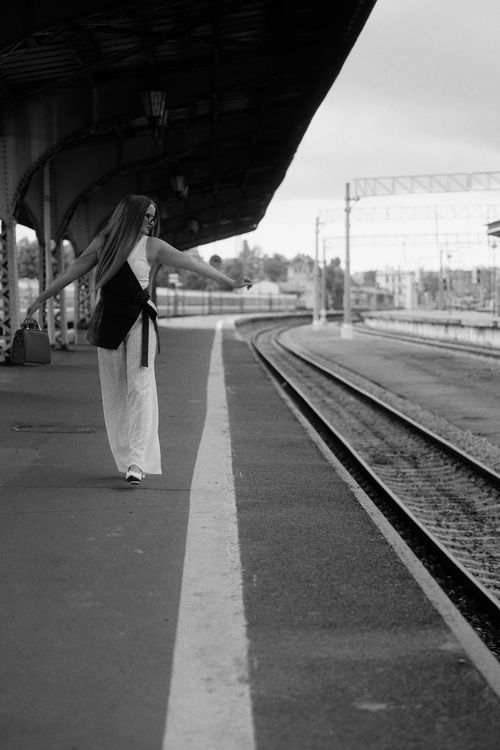 Free Stylish young woman walking alone on a deserted platform, captured in black and white. Stock Photo