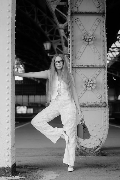 Free Black and white portrait of a woman in a trendy outfit standing in a vintage station. Stock Photo