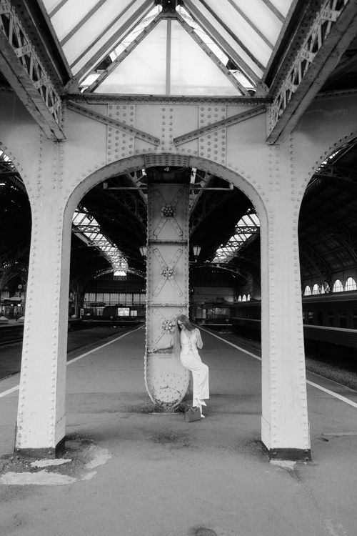 Free Black and white photo of a woman in an elegant dress at an empty train station. Stock Photo