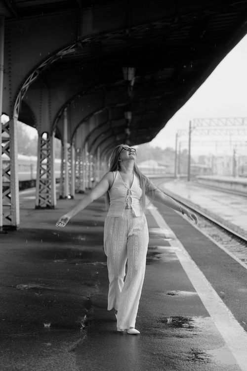 Free Happy woman enjoying rain at a train station, embracing the moment. Stock Photo
