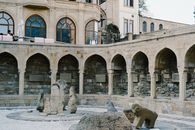 Ancient stone sculptures in historic arched courtyard with beige tones.