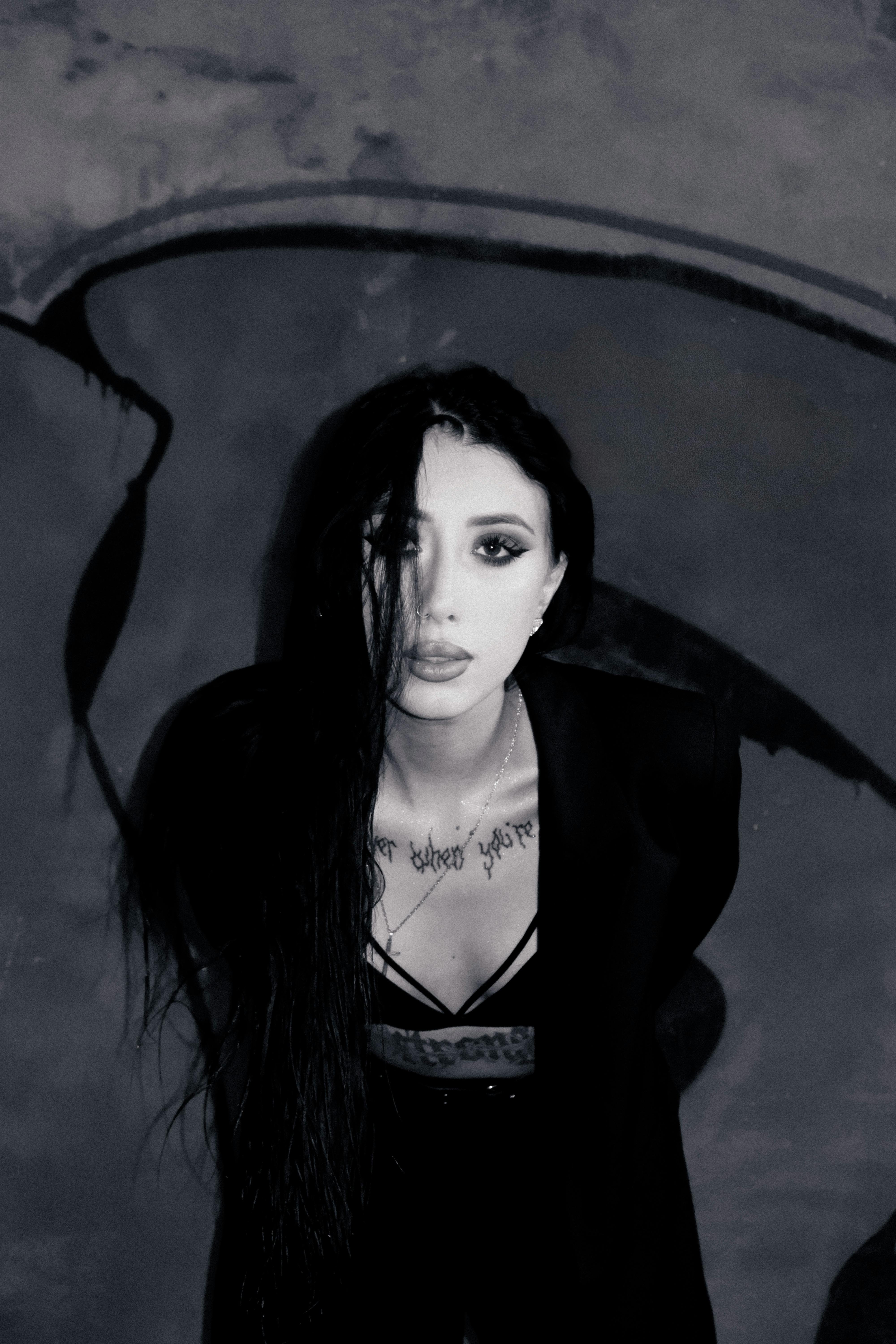Black and white portrait of a woman with long hair against a graffiti wall.