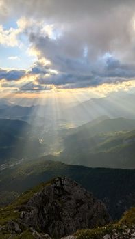 Breathtaking view of sunlight streaming through clouds over the Austrian Alps, perfect for nature and travel imagery.