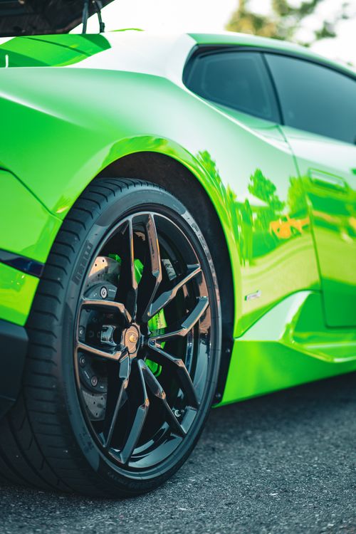 Free Close-up of a bright green sports car showcasing sleek, modern rims. Captures luxury and speed. Stock Photo