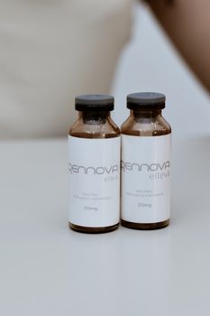Brown glass bottles with 'Renova Elleva' label on a white table. Clean and minimal.
