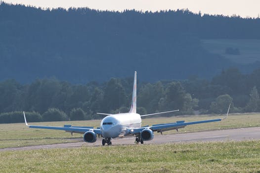 A commercial airliner prepares for takeoff at Poprad Airport with a scenic mountain backdrop.