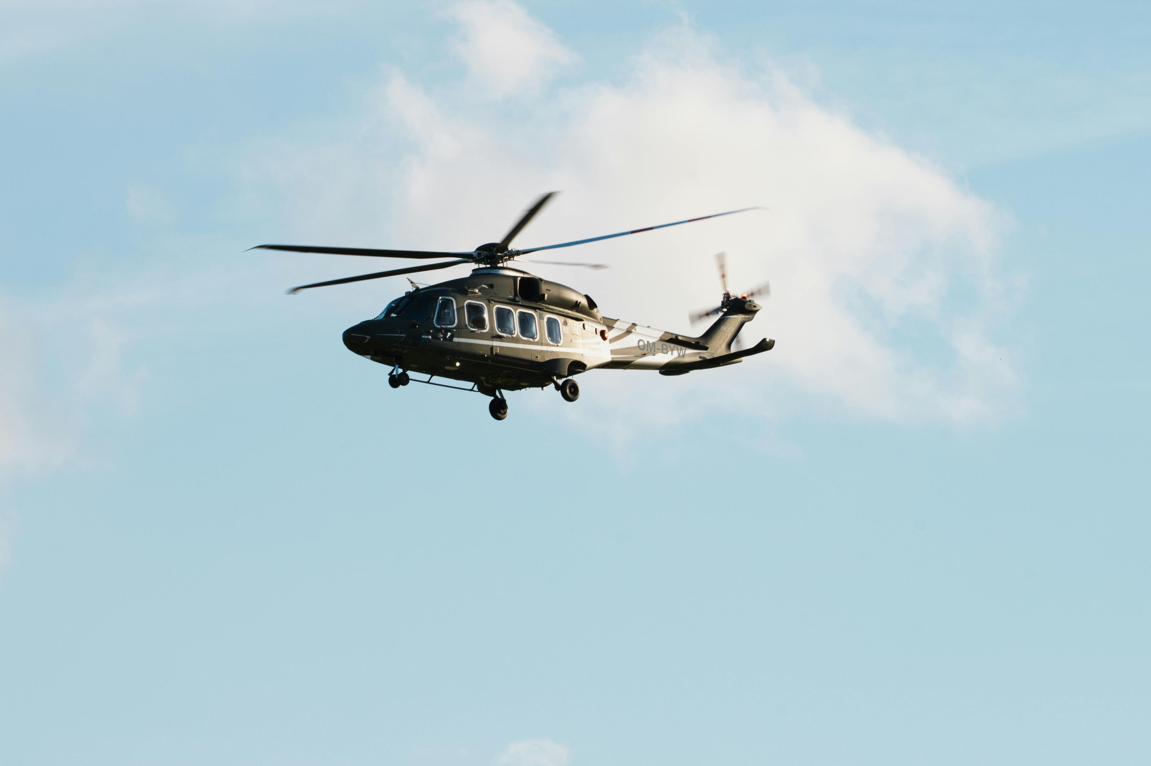 A helicopter in flight against a backdrop of clear blue sky and clouds in Poprad, Slovakia.