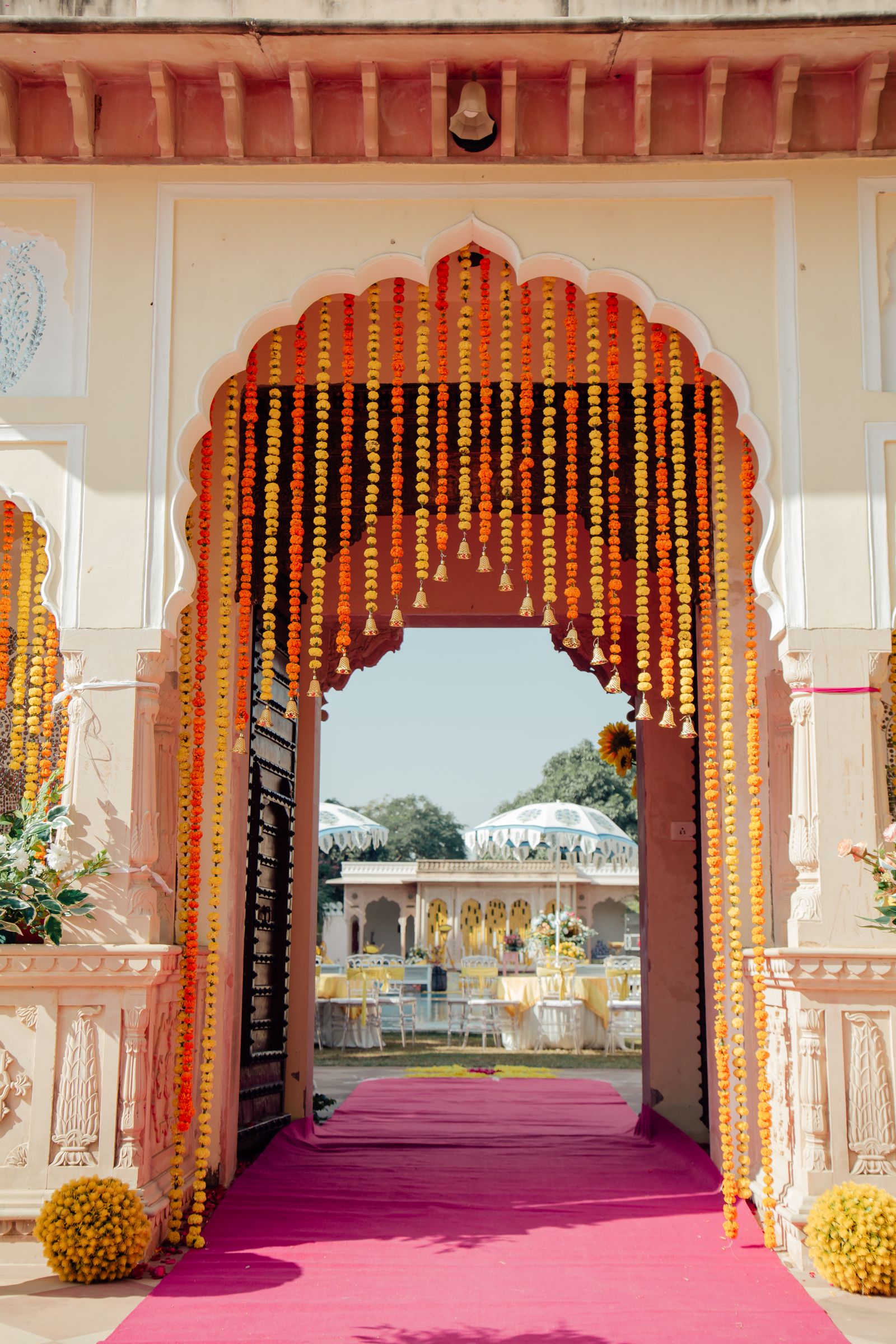 Marigold-garlanded entrance archway at an outdoor wedding venue