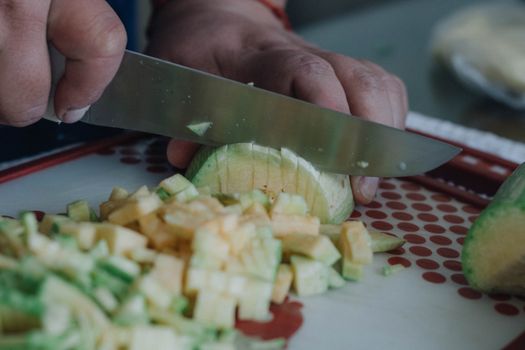Hands slicing fresh green squash on a cutting board, showcasing culinary skills and food preparation.