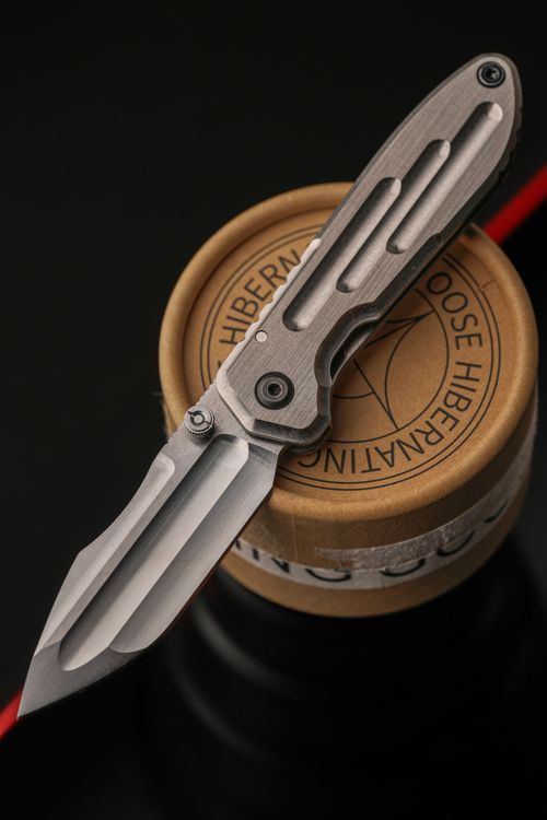 Free Elegant close-up of a modern folding knife resting atop a circular object, showcasing craftsmanship. Stock Photo
