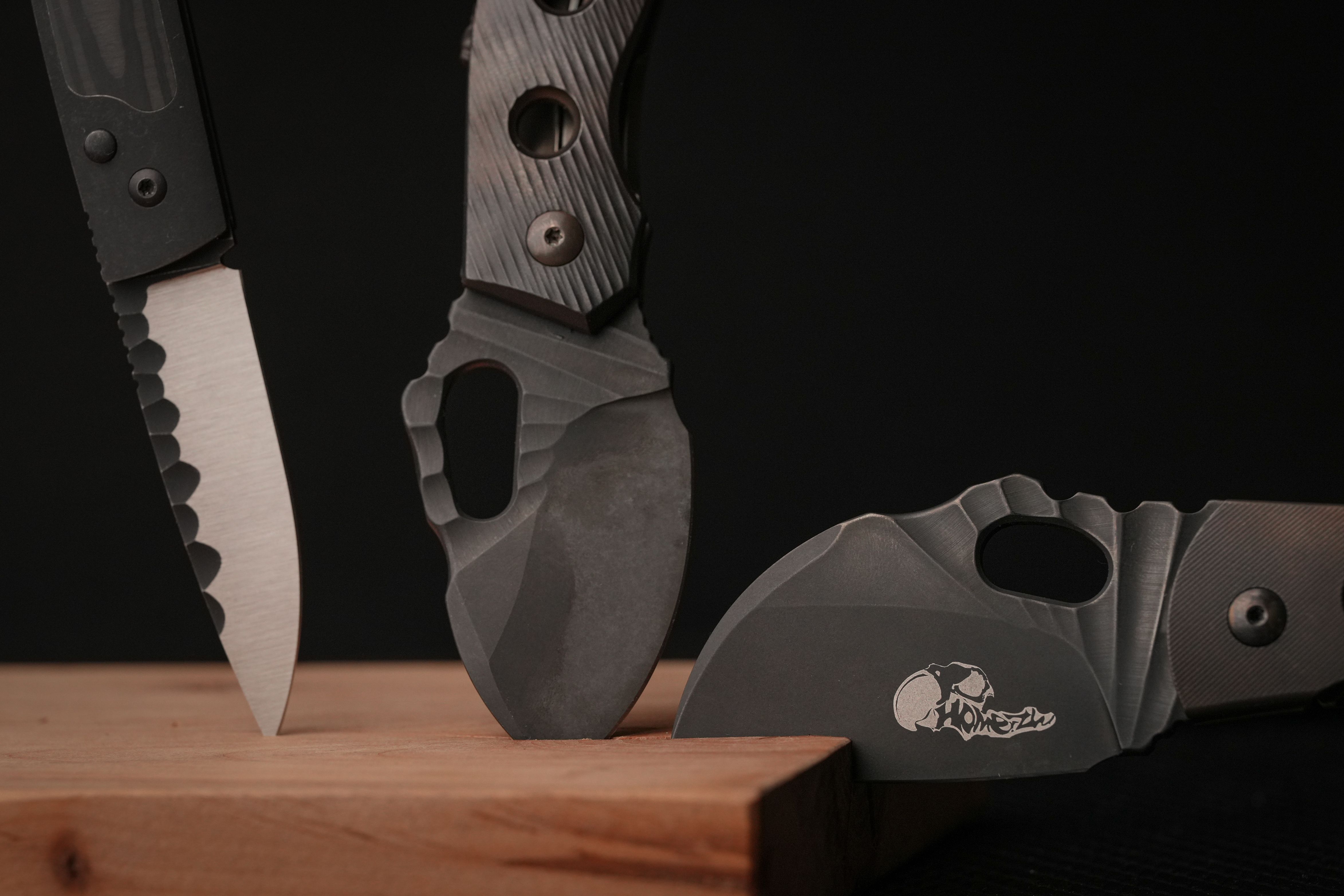 A sharp and sleek display of three modern tactical knives set against a dark background.