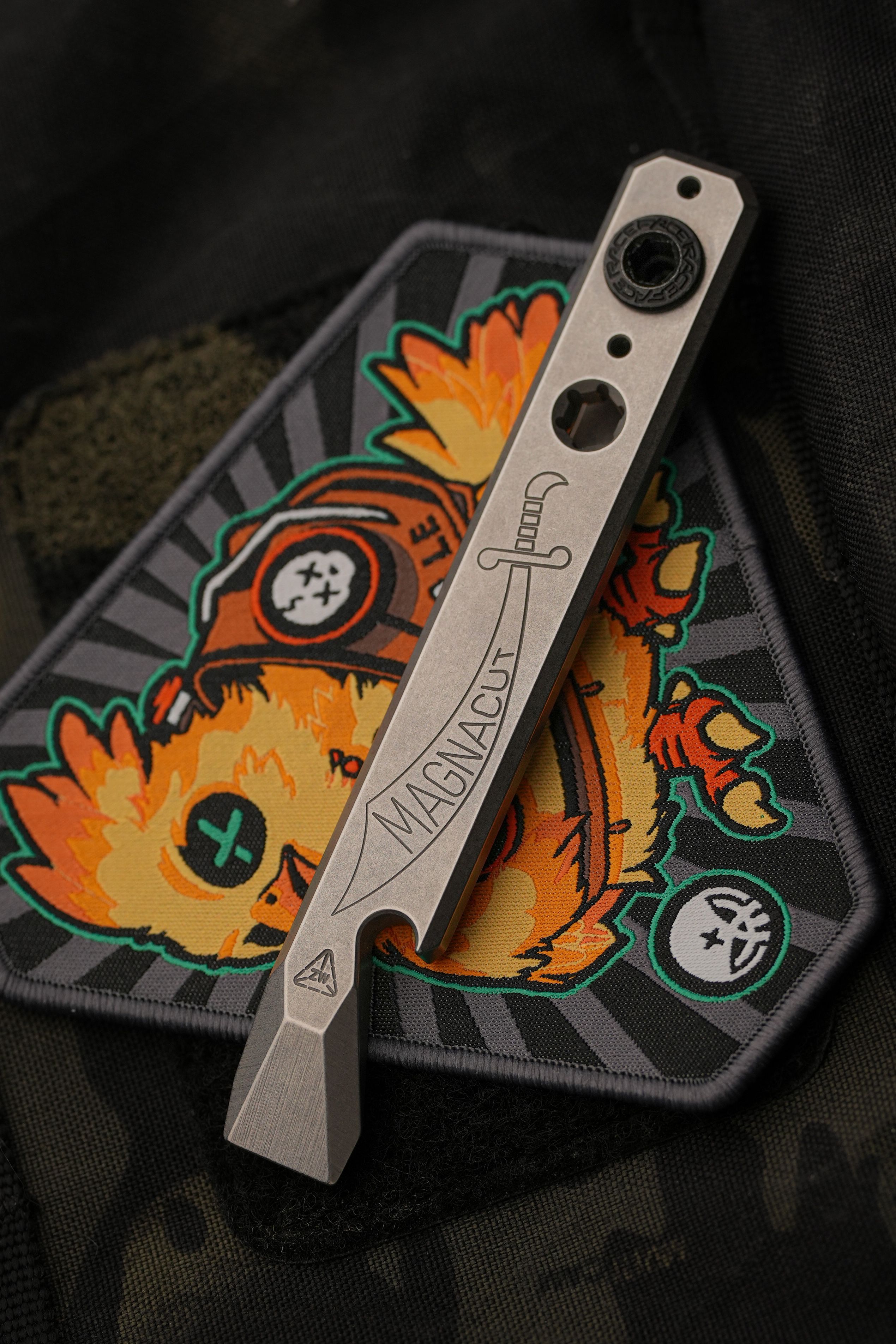 A compact EDC multitool resting on a patch, showing a slim pocket-ready profile