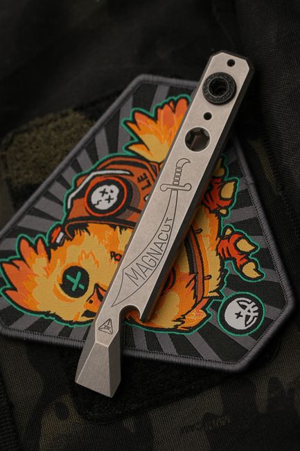 A compact EDC multitool resting on a patch, showing a slim pocket-ready profile