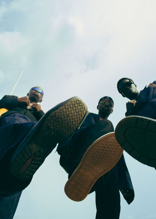 Free Three stylish men in sunglasses viewed from a low angle outdoors, exuding confidence. Stock Photo