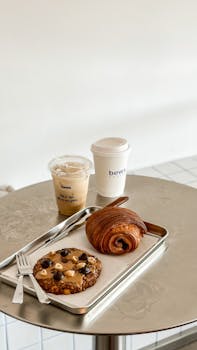 A delicious breakfast setup featuring a pastry, iced coffee, and a hot drink on a sleek table.