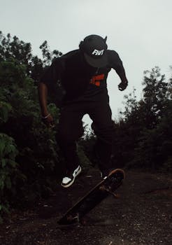 Young man performing an impressive skateboard trick in a lush, outdoor setting.