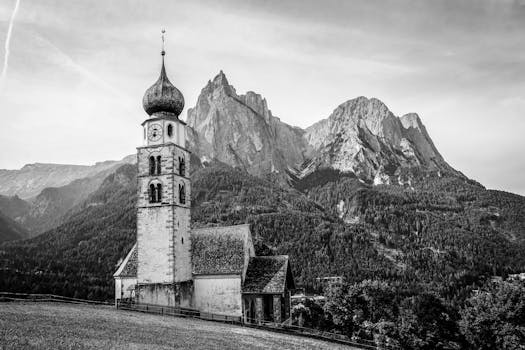 A black and white image of a church against a stunning mountain backdrop in South Tyrol.