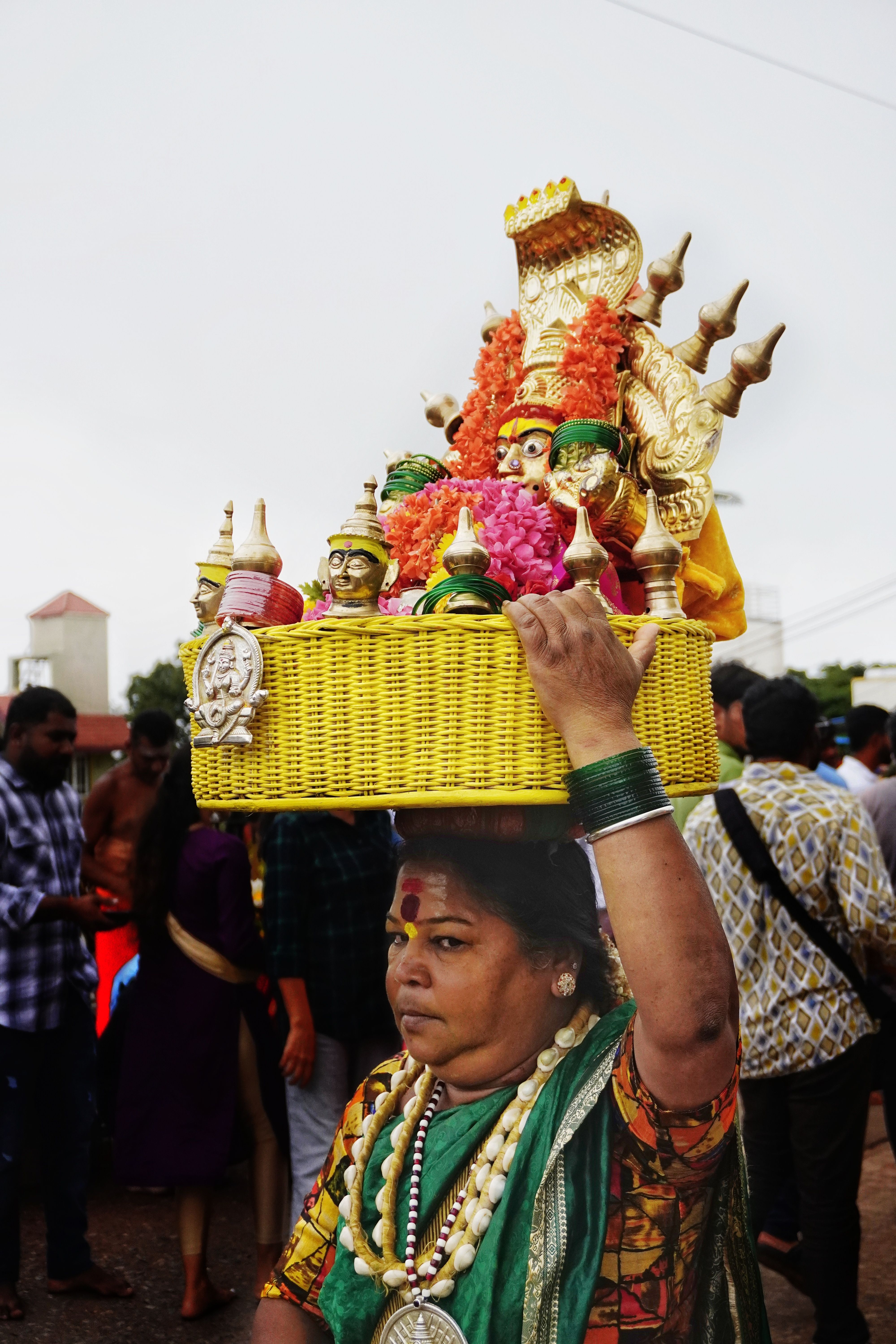 Woman with decorative basket during a cultural festival in a vibrant street.