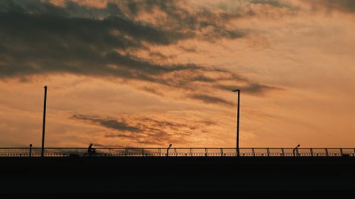 Free Silhouette of a cyclist on a bridge at sunset with dramatic sky. Stock Photo