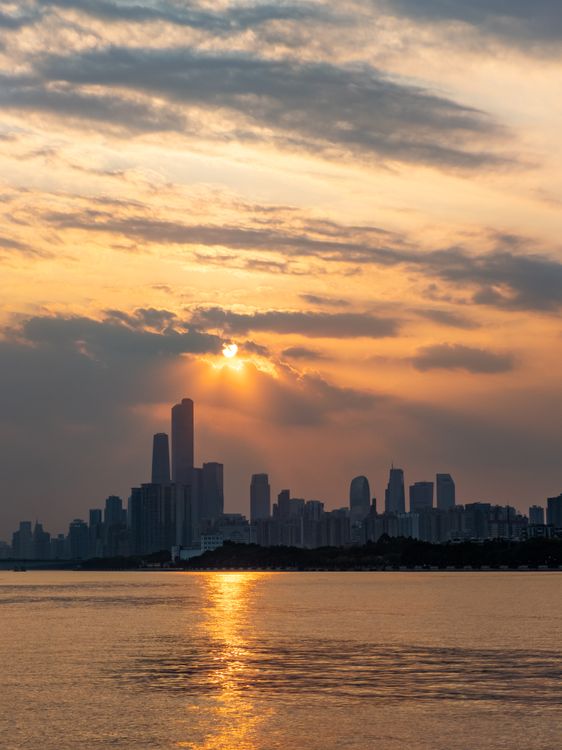 Dramatic City Skyline at Sunset Over Water · Free Stock Photo