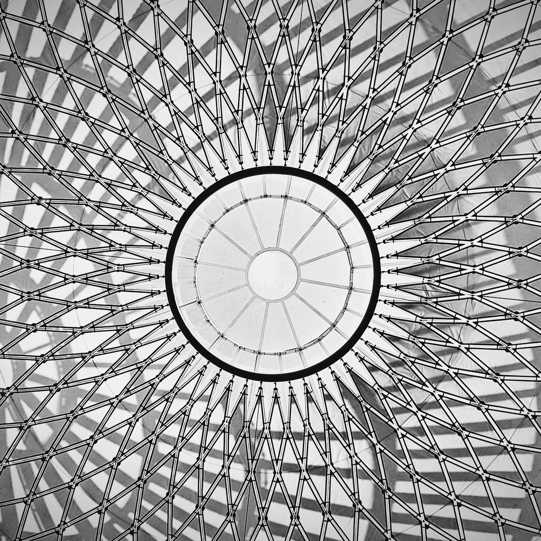 Black and white photo of a dome ceiling featuring a symmetrical geometric pattern with radiating lines.