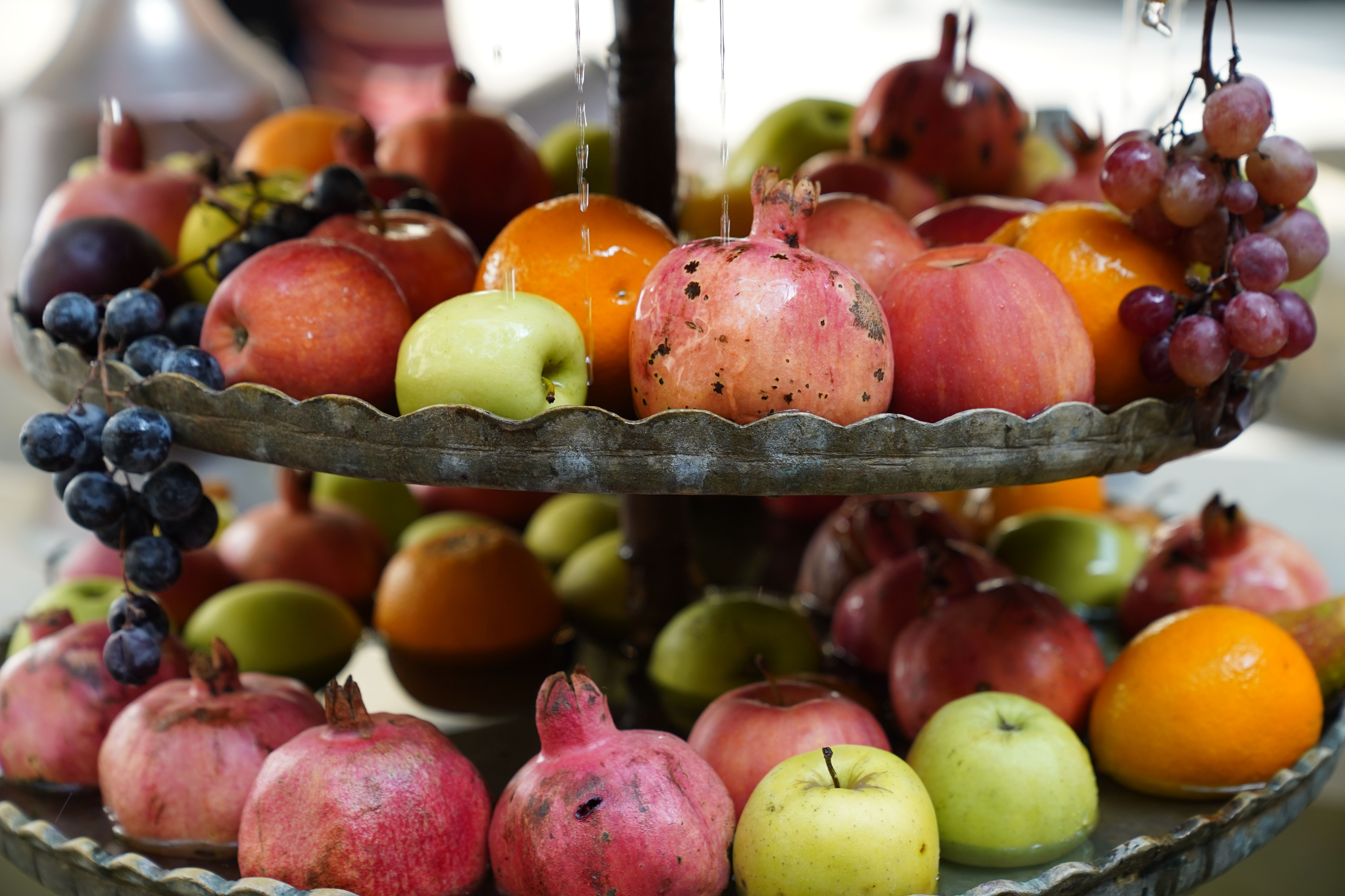 Tiered Fruit and Produce Stand DIY home decor project — A colorful array of fresh fruits including pomegranates, grapes, apples, and oranges on a vintage two-tier tray.