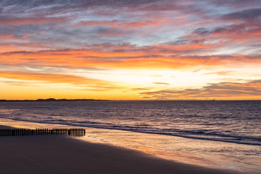 Stunning sunrise over Torquay Beach, Victoria, Australia with vibrant colors and calm ocean waves.