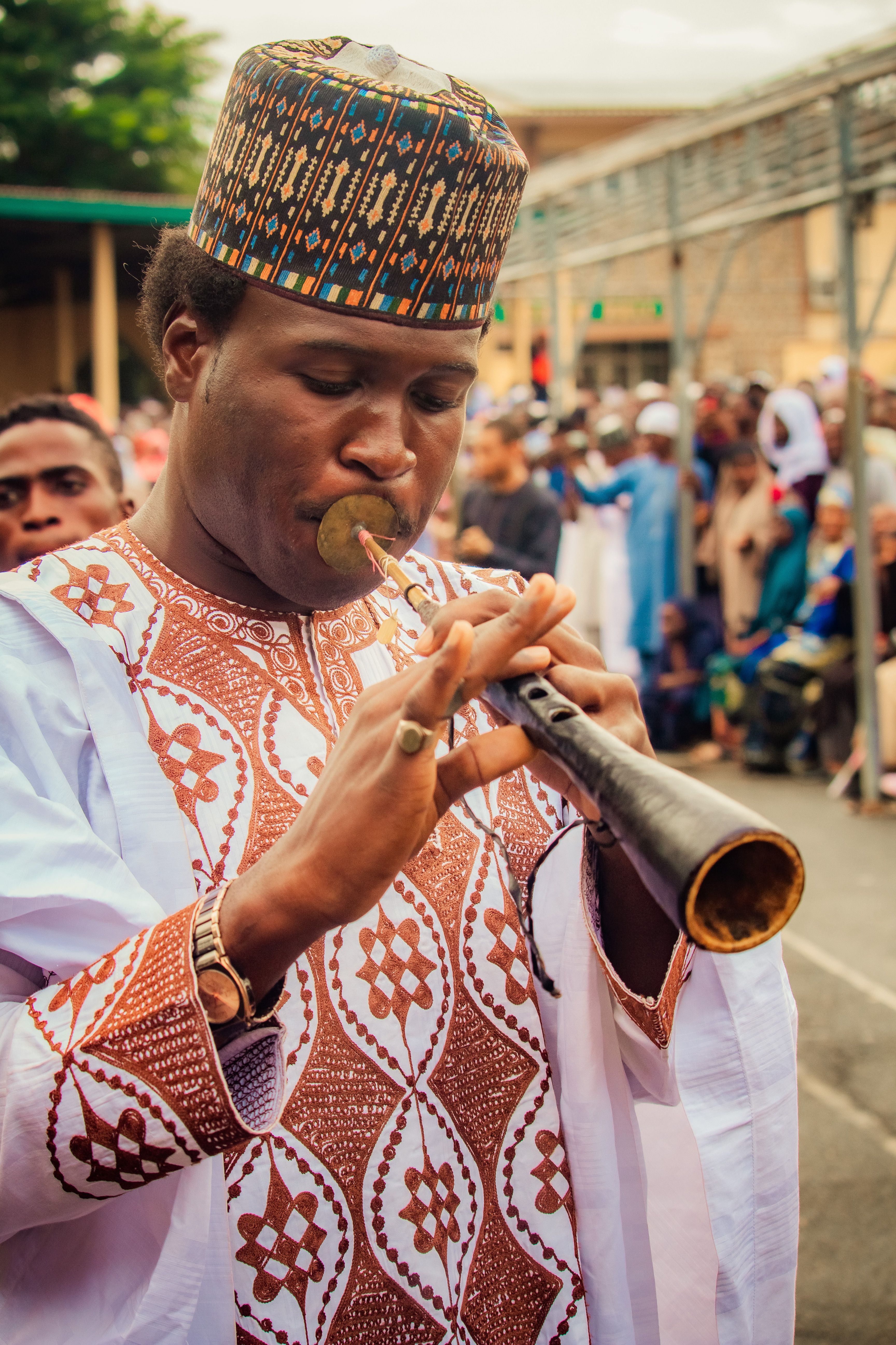 A musician performing on a traditional flute during a vibrant Nigerian street festival.