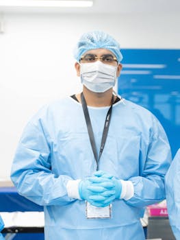 Doctor in surgical scrubs and mask standing in clinic environment.