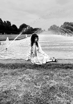 Black and white photo of a woman by a fountain in Düsseldorf.