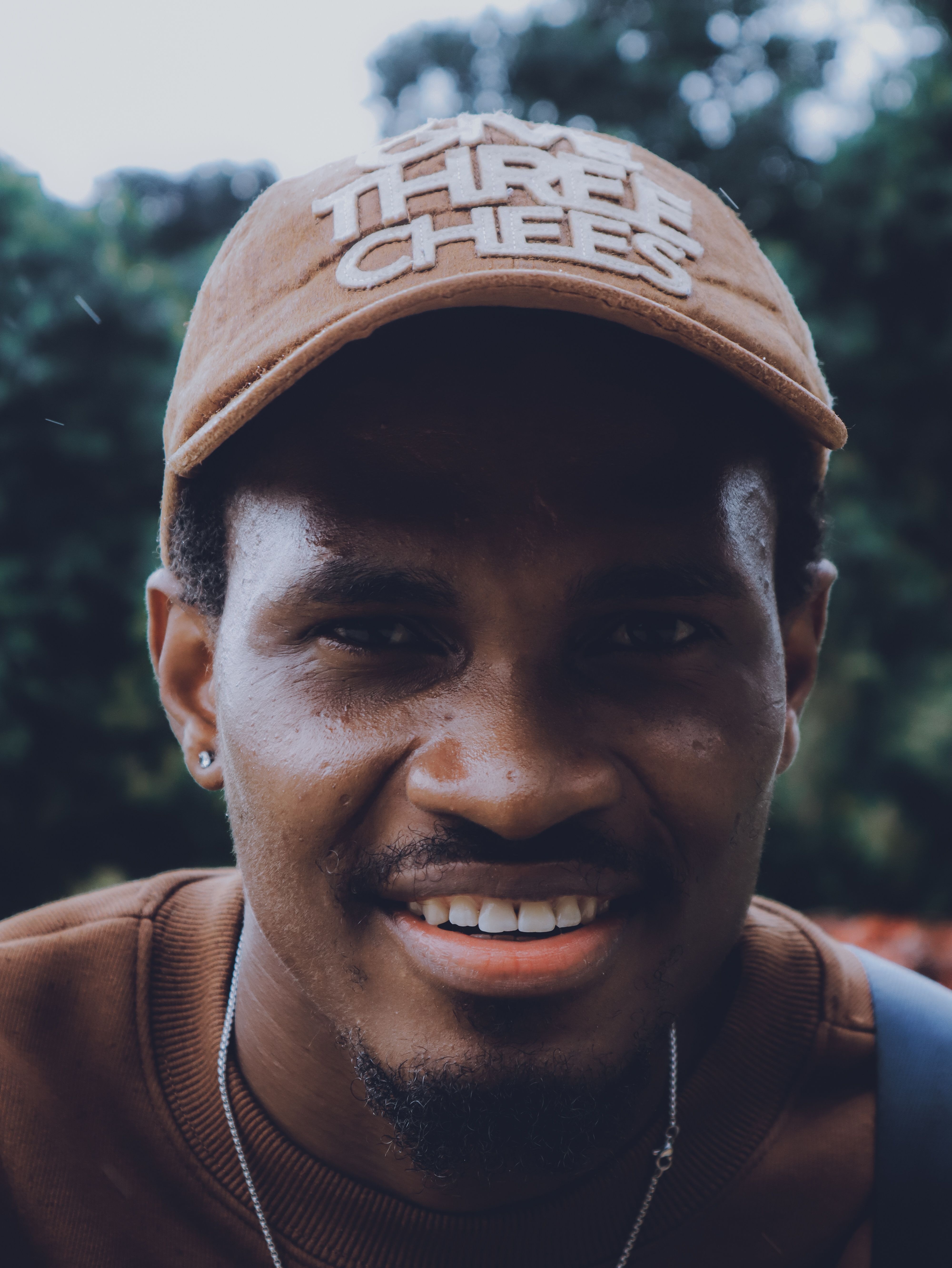 Portrait of a smiling man wearing a brown cap outdoors in Abuja, Nigeria.