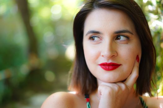 Close-up portrait of a woman with red lipstick enjoying a garden setting in Sintra, Portugal.