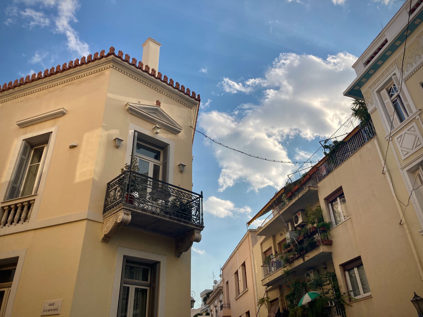 Explore the classic architecture of Athens with charming vintage balconies against a bright blue sky.