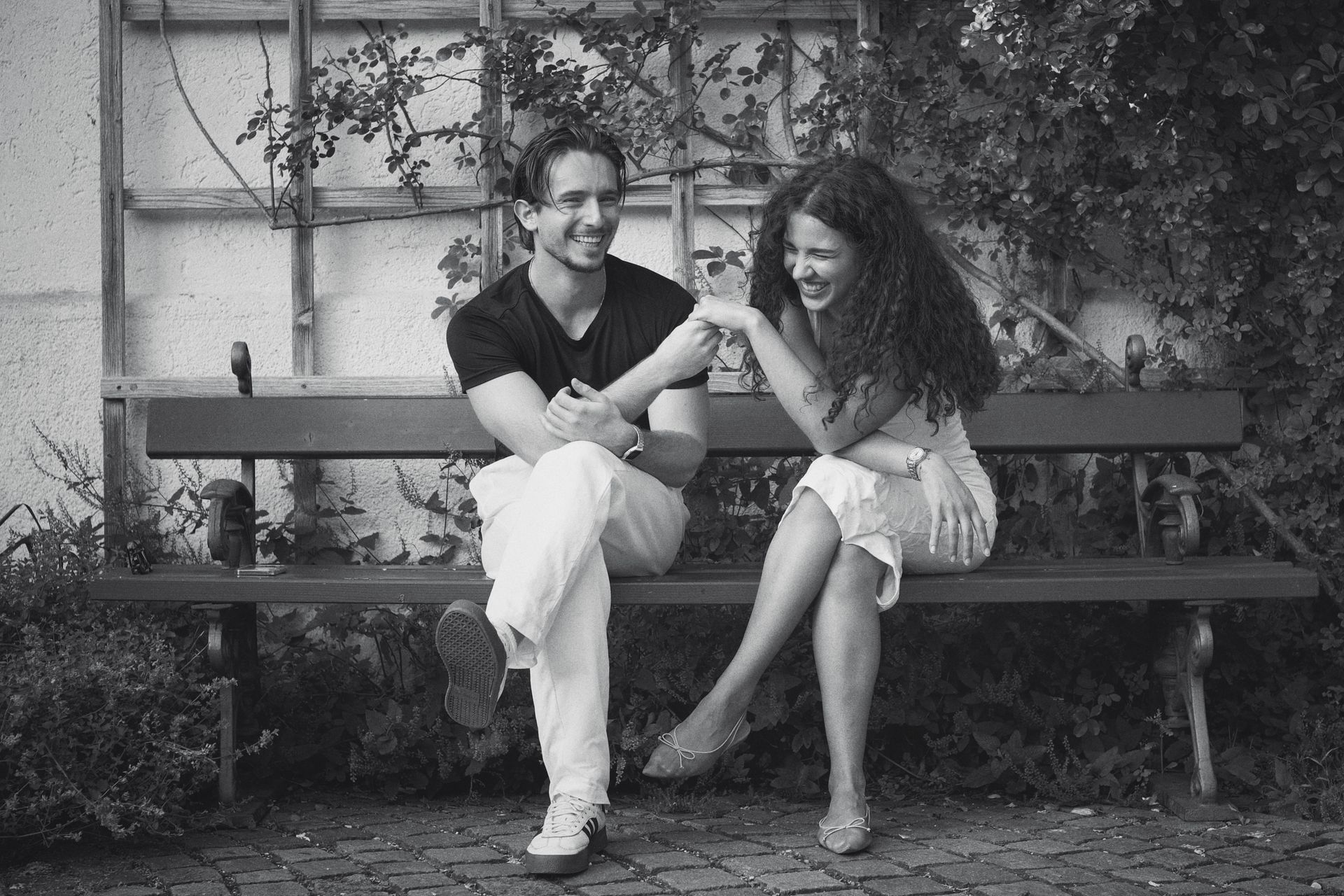 Candid moment of a joyful couple laughing together on a park bench, black and white style.