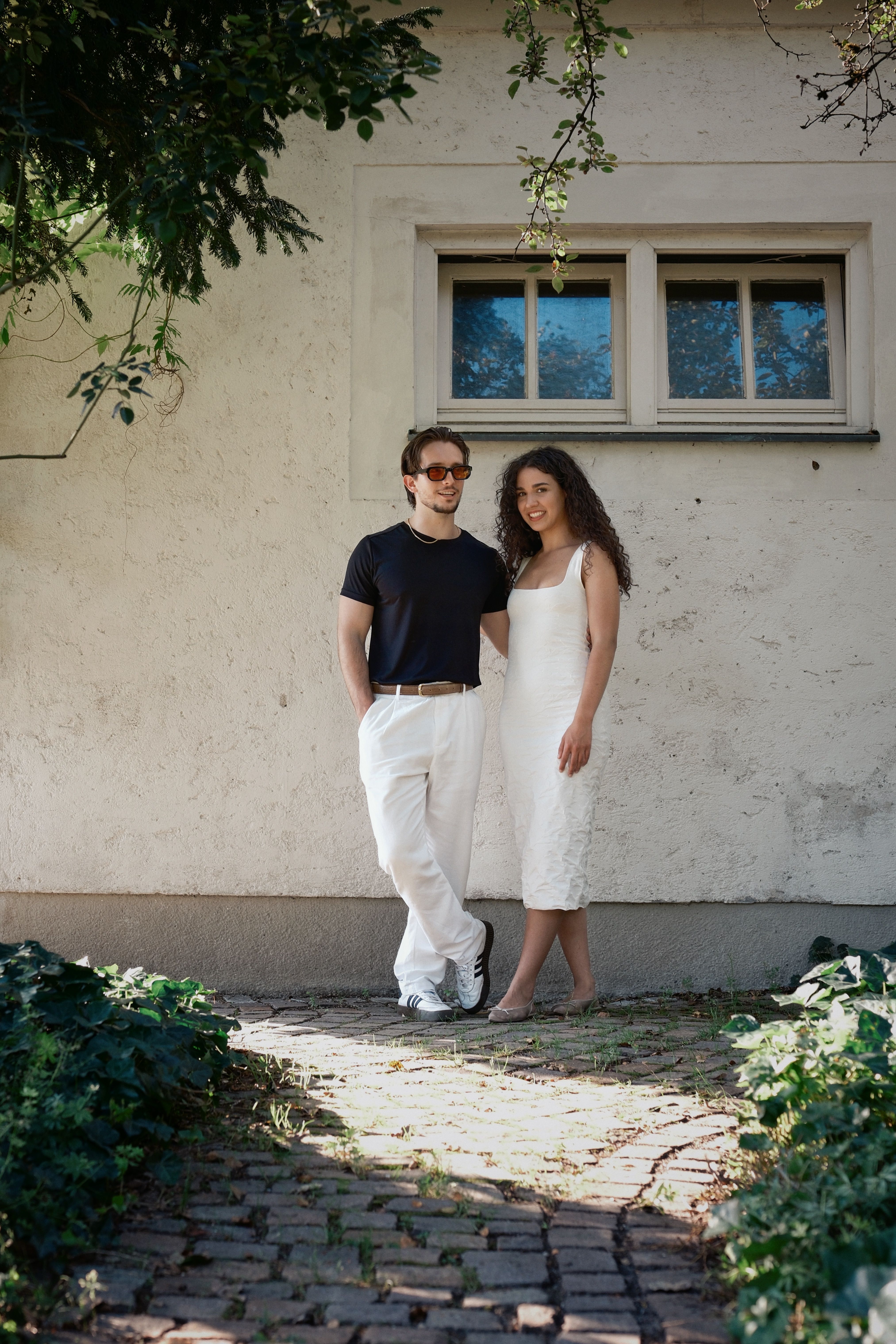 Happy couple standing outside a rustic cottage, enjoying sunny day.