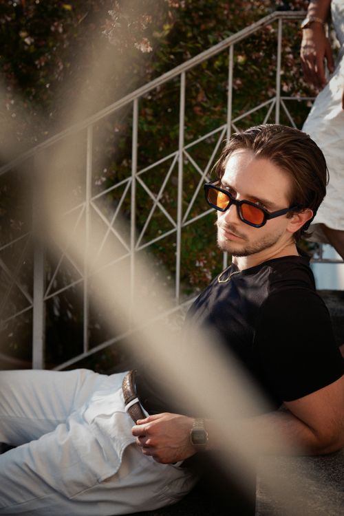 Free Man in sunglasses leaning on stairs, enjoying a sunny day outdoors. Stock Photo