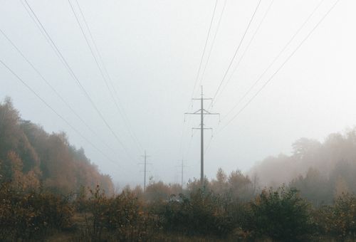 Free Misty autumn scene featuring power lines in a foggy landscape with colorful foliage. Stock Photo