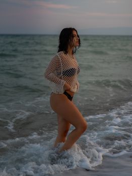 Woman in swimwear posing at Calabria beach during sunset, capturing tranquility and style.