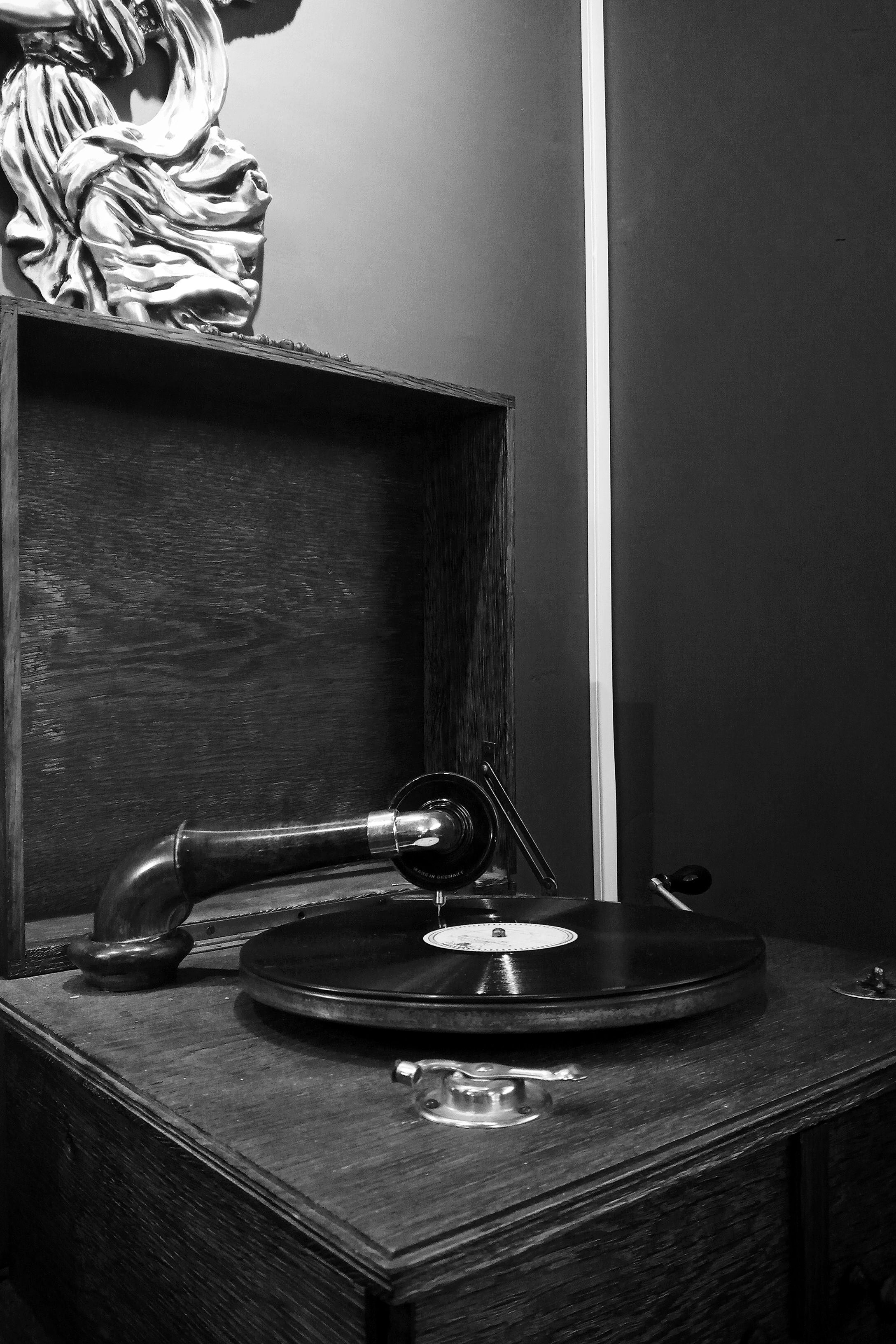 Fotomural Foto clásica en blanco y negro de un gramófono vintage y un disco de vinilo en un entorno nostálgico.
