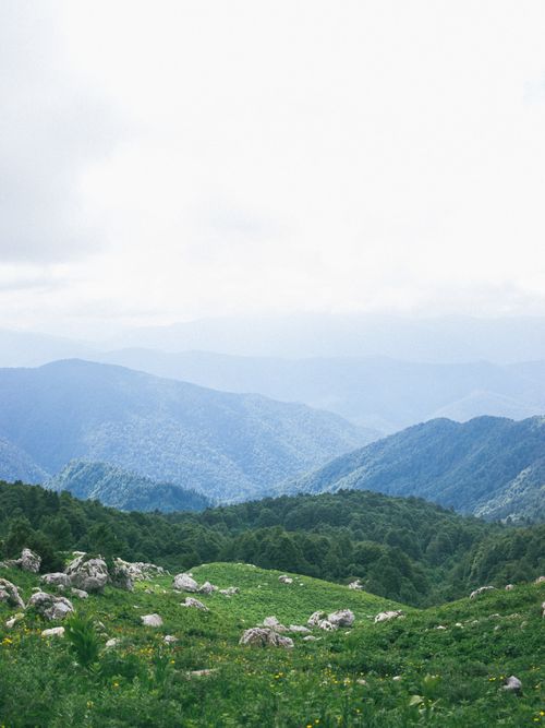 Free Lush green hills and distant mountain ranges create a serene landscape view. Stock Photo
