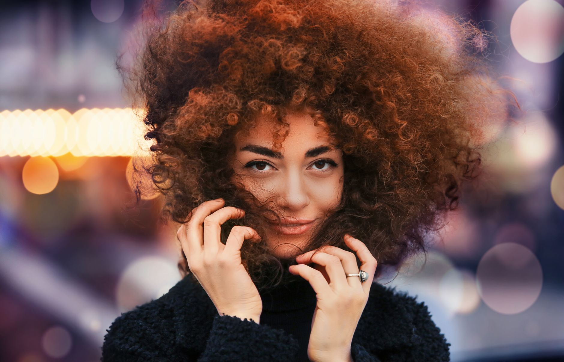 Captivating portrait of a woman with striking curly hair and elegant expression captured in soft evening light.