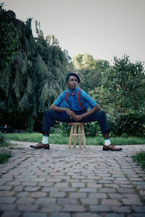 Free Young man seated on a stool outdoors in a serene garden. Stock Photo