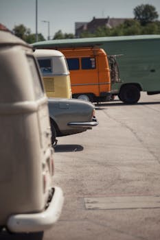 A row of vintage camper vans parked outdoors on a sunny day, showcasing retro vehicle design and travel vibes.