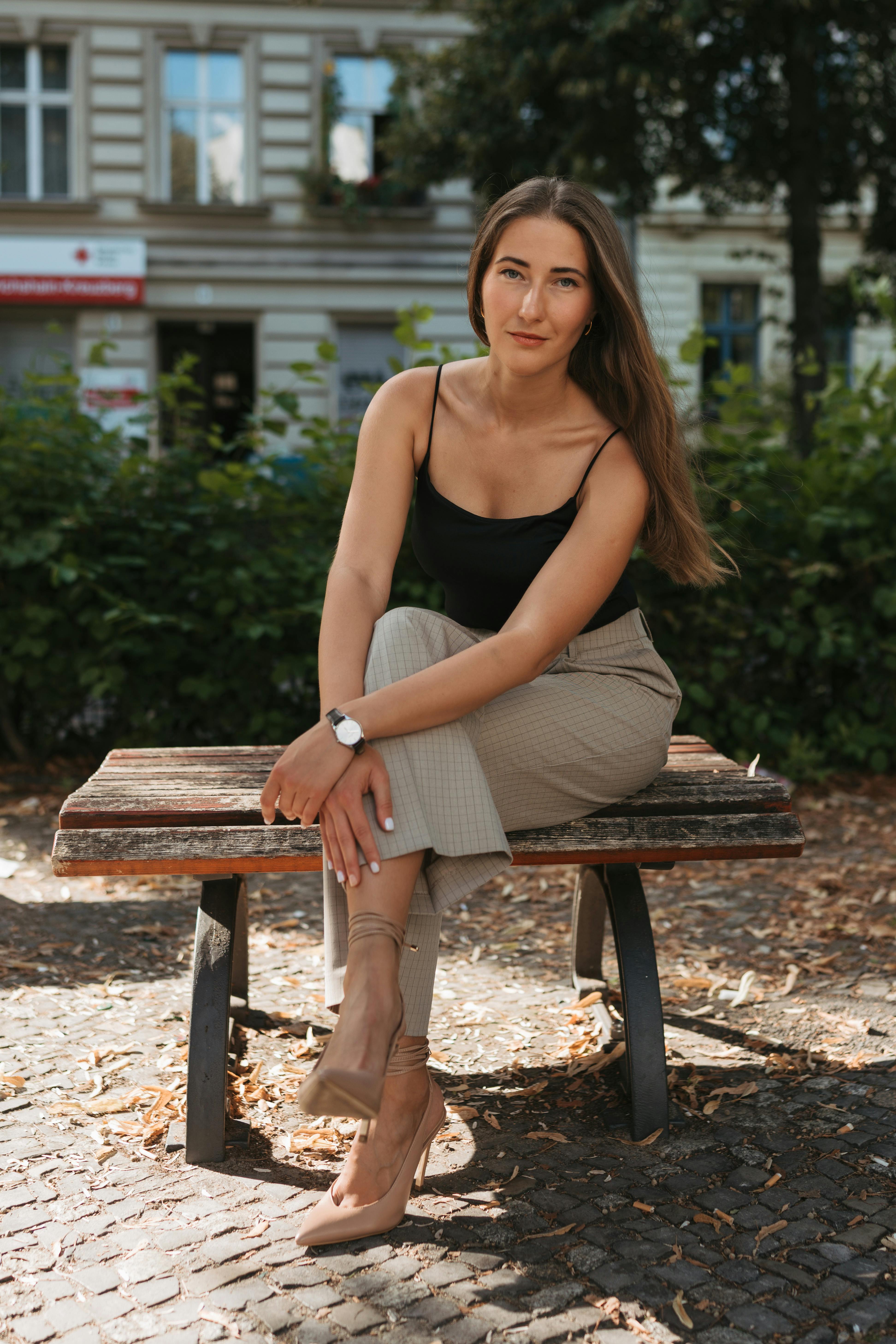 Chic fashion portrait of a woman sitting on a bench in sunny Berlin, Germany.